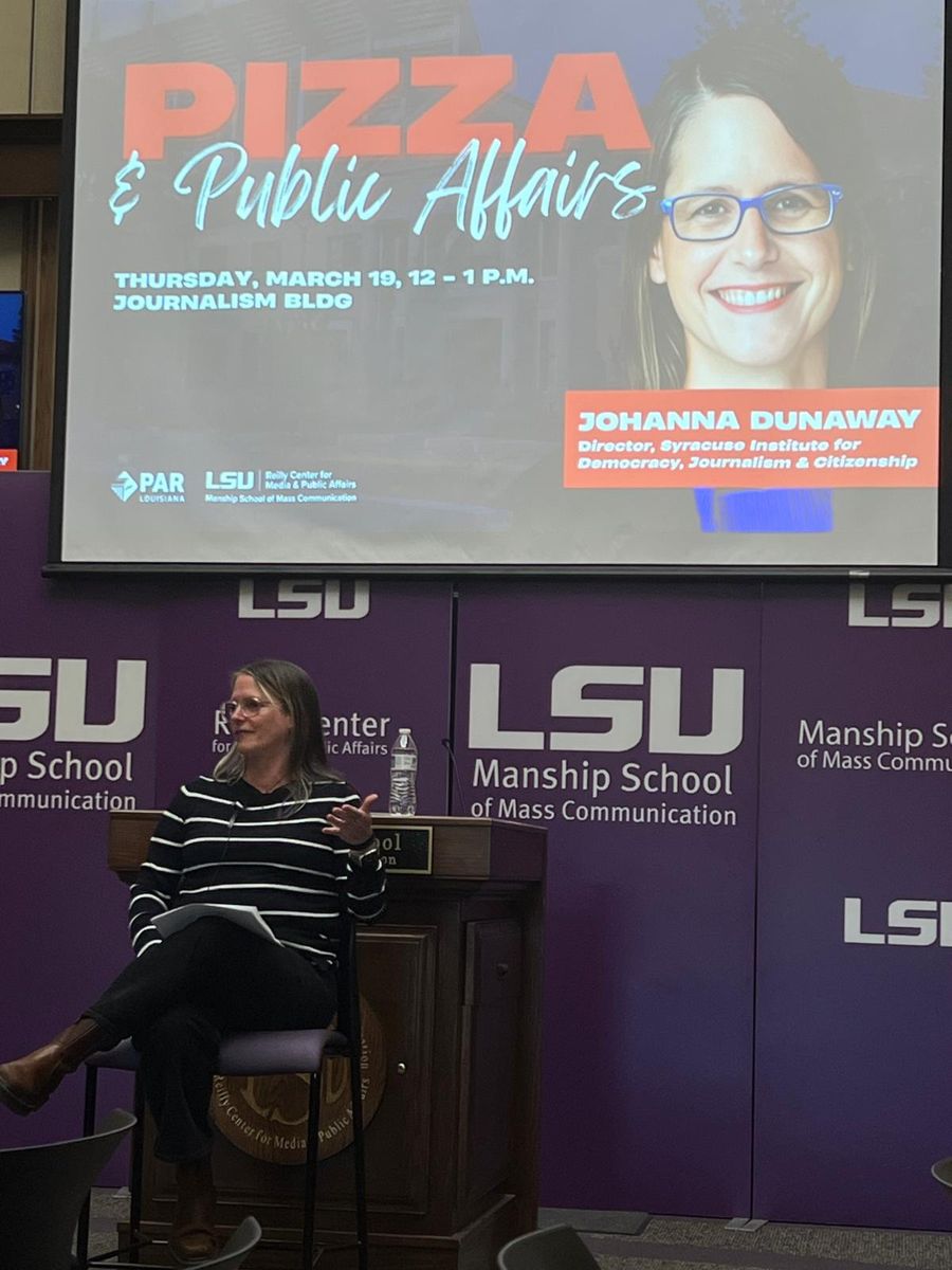 Johanna Dunaway speaking at LSU's Pizza & Public Affairs event in front of the Manship School backdrop